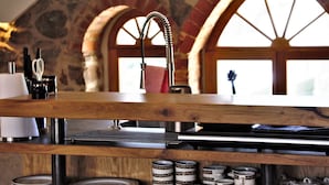 A kitchen with a stone wall, wooden counter, and a window with a view. - Architektenwohnung mit Privatsauna (Großharthau)