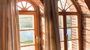 A room with two arched windows, wooden doors, and a stone wall. - Architektenwohnung mit Privatsauna (Großharthau)
