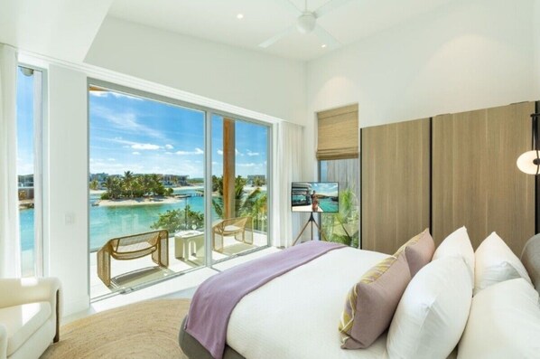 Camera d'albergo con un'ampia porta scorrevole in vetro che si apre su un balcone con vista sulla spiaggia e sull'oceano.
