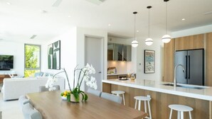 A modern kitchen with a wooden island, white bar stools, and a stainless steel refrigerator. - Turks Explorer’s Haven | Marine Excursions & Snorkeling Paradise | Pool & Spa (Long Bay Hills)