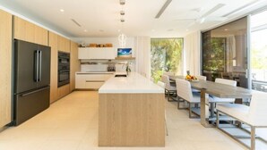 Une cuisine moderne dotée d’un îlot central, d’appareils électroménagers en acier inoxydable et d’un coin repas avec une grande table et des chaises.