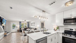 Uma cozinha moderna com armários brancos, eletrodomésticos de aço inoxidável e uma ilha central com pia.