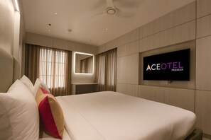 A hotel room with a large bed, a TV mounted on the wall, and a mirror above the bed. - Hotel Ujjayanta (Ujjain)