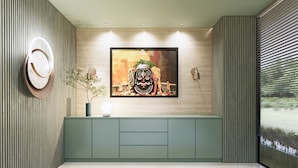 Una sala de estar moderna con un televisor de pantalla plana grande montado en una pared de madera, un mueble verde debajo y un espejo redondo a la izquierda.