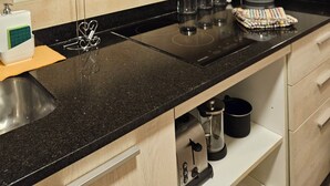 A kitchen with a black countertop, stainless steel appliances, and wooden cabinets. - Comfortable and central studio with view to Nahuel Huapi lake (San Carlos de Bariloche)