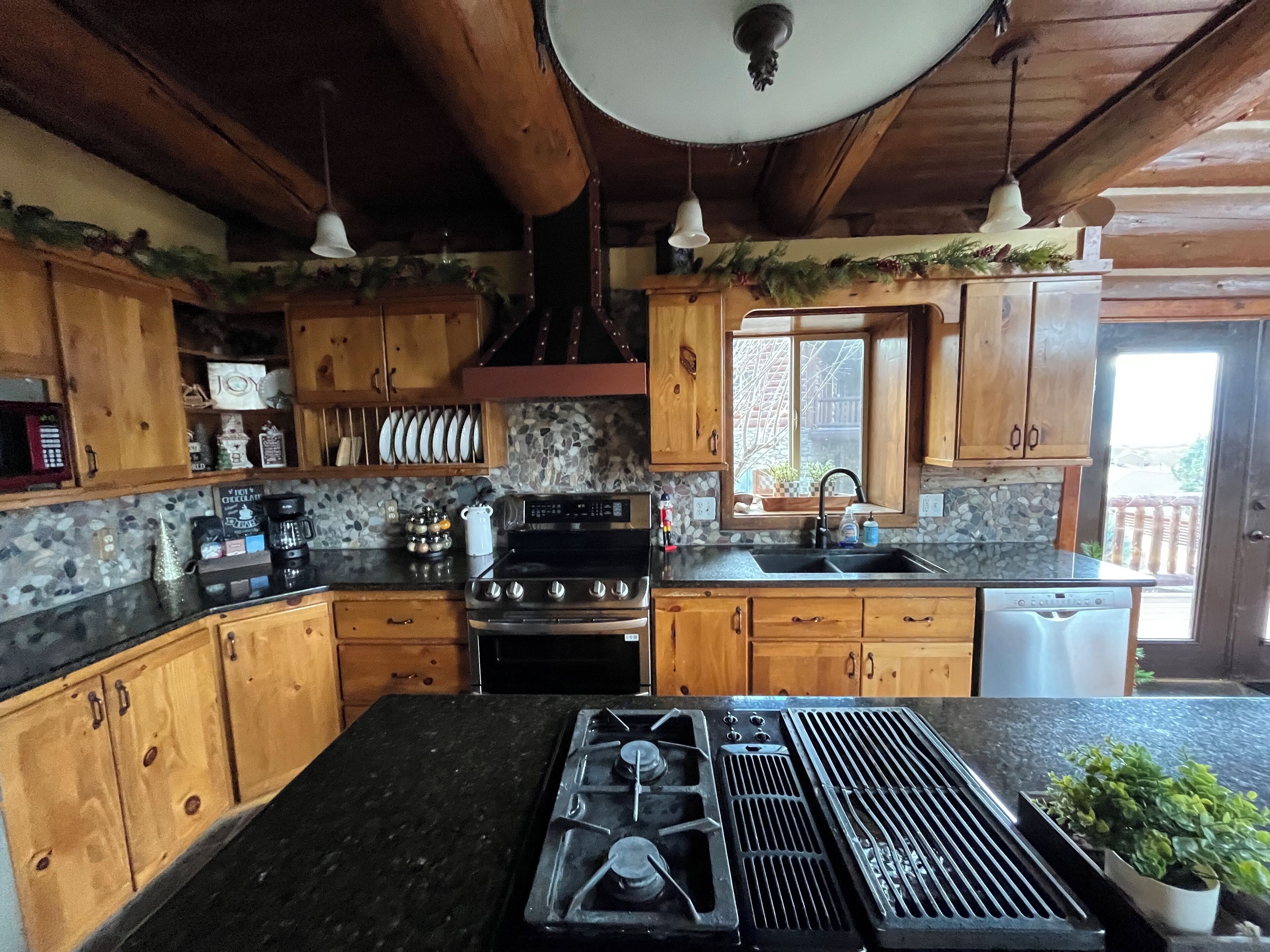 A kitchen with wooden cabinets, a stove, a sink, and a window.