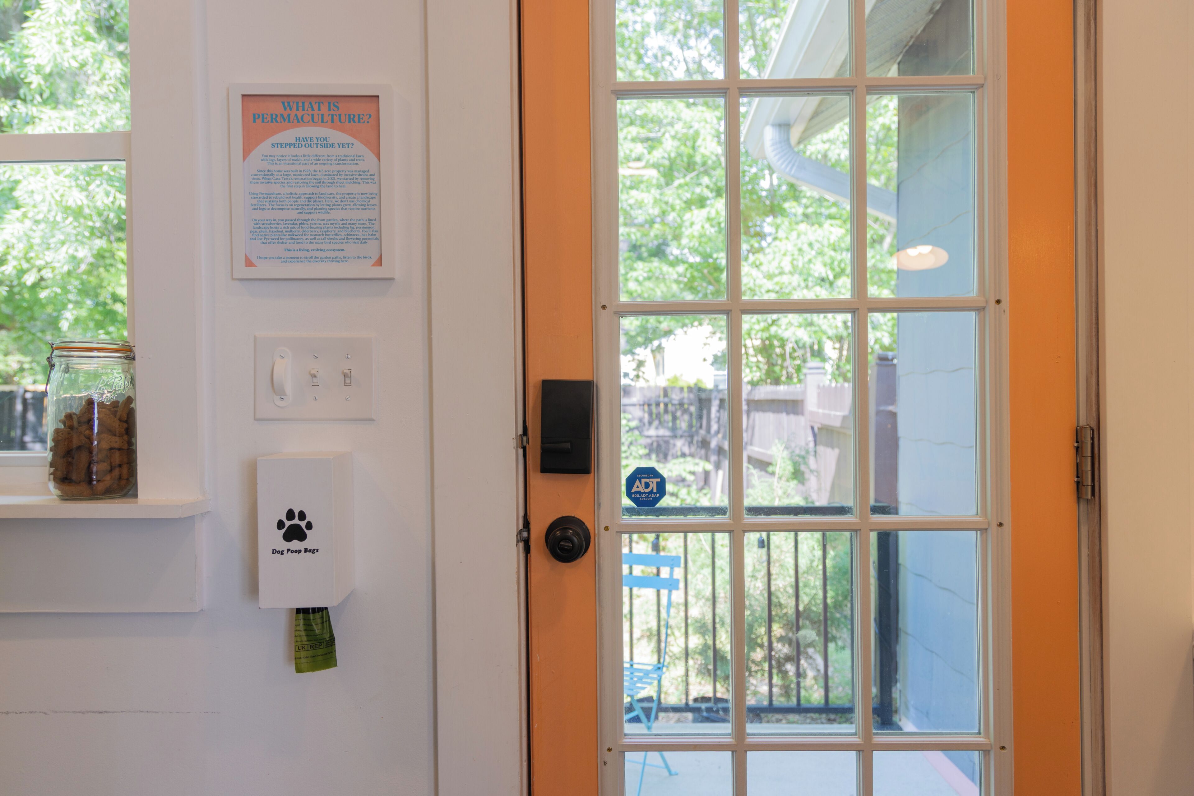 Una puerta con una ventana, un dispensador de bolsas para excrementos de perro y un cartel en la pared.