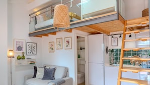Een modern loft appartement met een entresolbed, een keuken en een woonruimte met een bank en een salontafel.