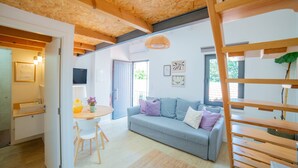 A modern interior with a wooden ceiling, a grey sofa, a small dining table, and a staircase. - VIVA VIVA Fontainhas Houses S (Porto)