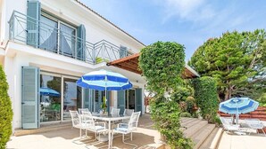 A two-story house with a patio area featuring a table and chairs, and two umbrellas.