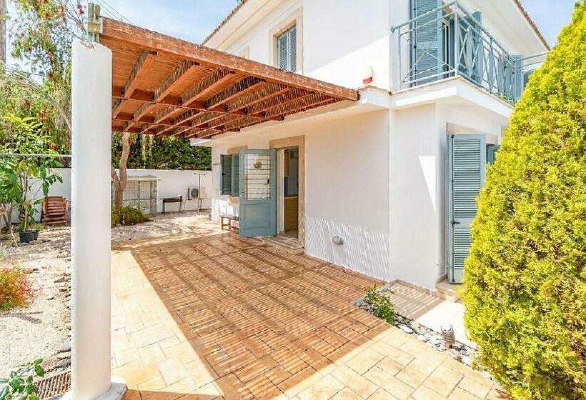 Ein Haus mit überdachter Terrasse, weißer Fassade und blauen Fensterläden.