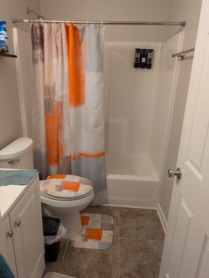 A bathroom with a shower, toilet, and a towel rack. - Cozy 3BR 1BA Basement (Conley)