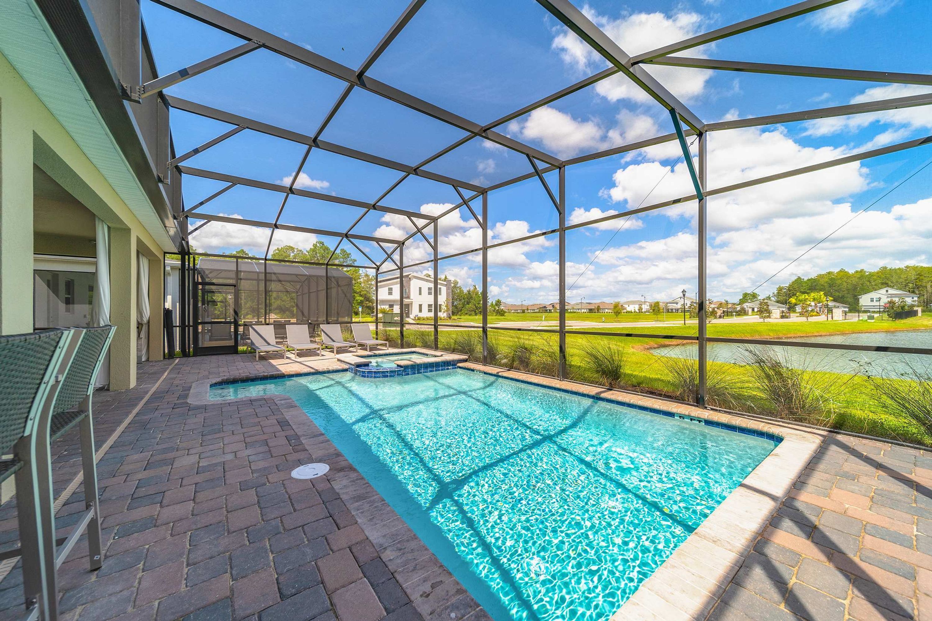 A covered outdoor swimming pool with a view of a lake and buildings in the background.