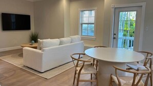 A living room with a white sofa, a round dining table, and wooden chairs. - 102 - Newly renovated house Oceanside  and Pool (Cudjoe Key)