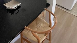 A modern living room with a black dining table, two wooden chairs, a white sofa, and a flat-screen TV mounted on the wall. - 102 - Newly renovated house Oceanside  and Pool (Cudjoe Key)