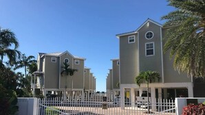 A gated residential complex with multiple two-story houses, a central driveway, and palm trees. - 105 - Newly renovated house Oceanside  and Pool (Cudjoe Key)