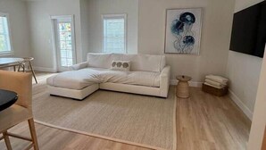 A modern living room with a sectional sofa, a dining area with a table and chairs, and a large abstract painting on the wall. - 103- Newly Renovated House with Oceanview and Pool (Cudjoe Key)