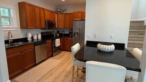 A modern kitchen with wooden cabinets, stainless steel appliances, and a black countertop. - 103- Newly Renovated House with Oceanview and Pool (Cudjoe Key)