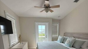 A bedroom with a bed, a ceiling fan, a TV, and a window with blinds. - 103- Newly Renovated House with Oceanview and Pool (Cudjoe Key)