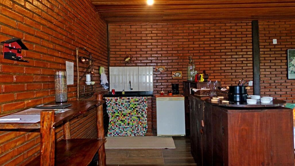 Cocina rústica con paredes de madera y salpicadero de ladrillo, que incluye un refrigerador, una cafetera y diversos utensilios de cocina.