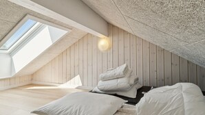 A loft bedroom with a sloped ceiling, wooden walls, and a skylight. - Gorgeous home in Glesborg with sauna (Glesborg)