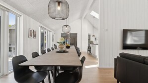 A modern dining area with a long table, black chairs, and pendant lighting. - Gorgeous home in Glesborg with sauna (Glesborg)