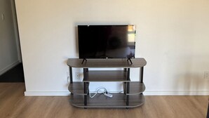Een flatscreen televisie op een houten tv-meubel tegen een effen muur.