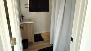 Een kleine badkamer met een wastafel, spiegel en een zwart douchegordijn.