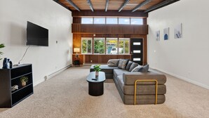 A modern living room with a sectional sofa, a coffee table, and a flat-screen TV. - Mid-Century Escape, Near Forest Park (Portland)