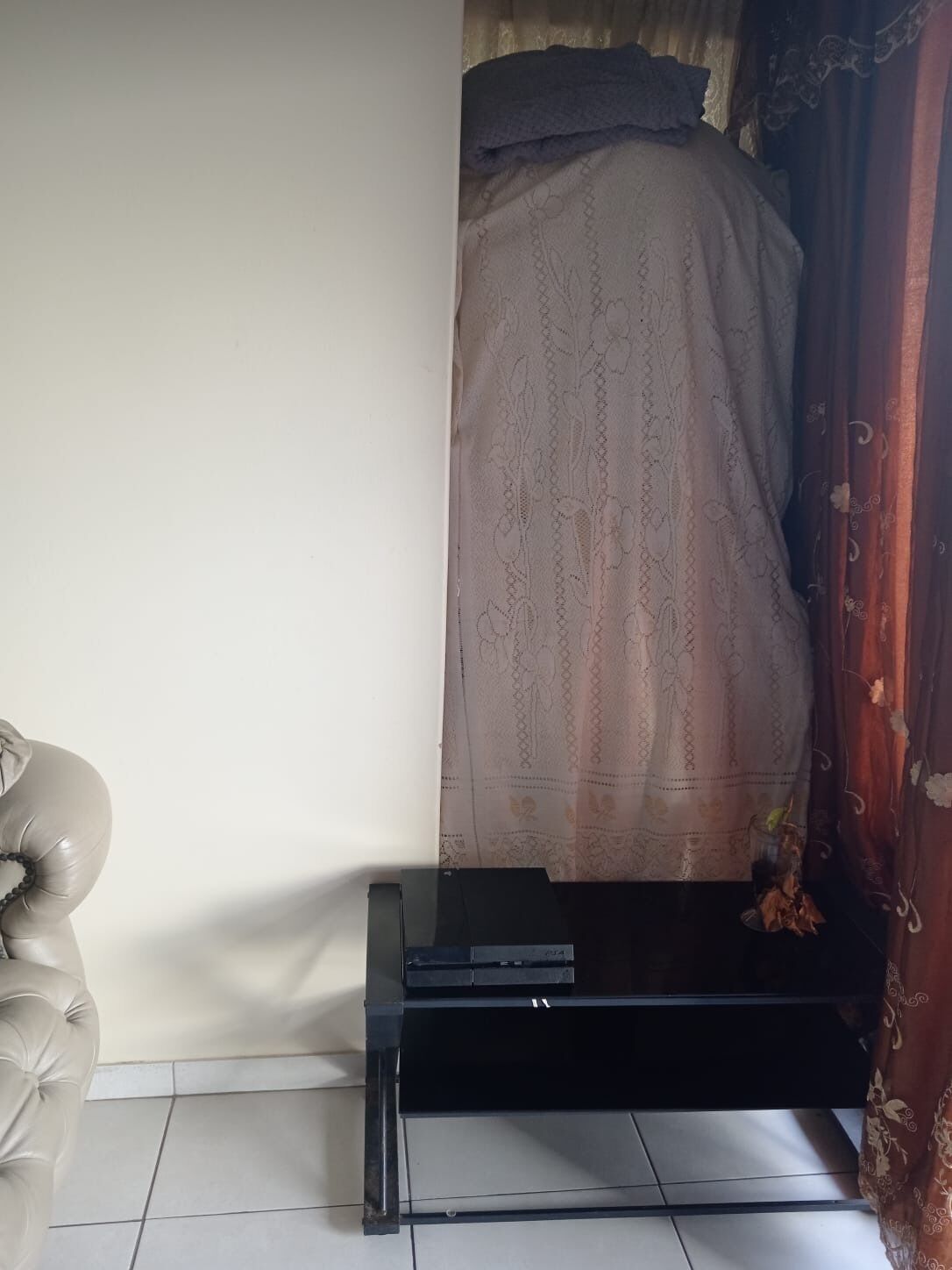 Une chambre à coucher avec un lit recouvert d’une couette à motifs floraux, une table de chevet noire et un mur blanc.