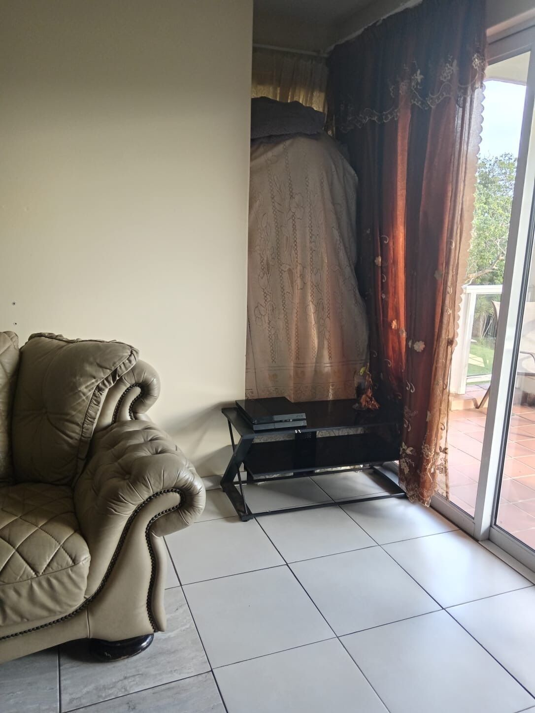 Ein Wohnzimmer mit einem beigen Sofa, einem schwarzen Couchtisch und einem großen Fenster mit Vorhängen.