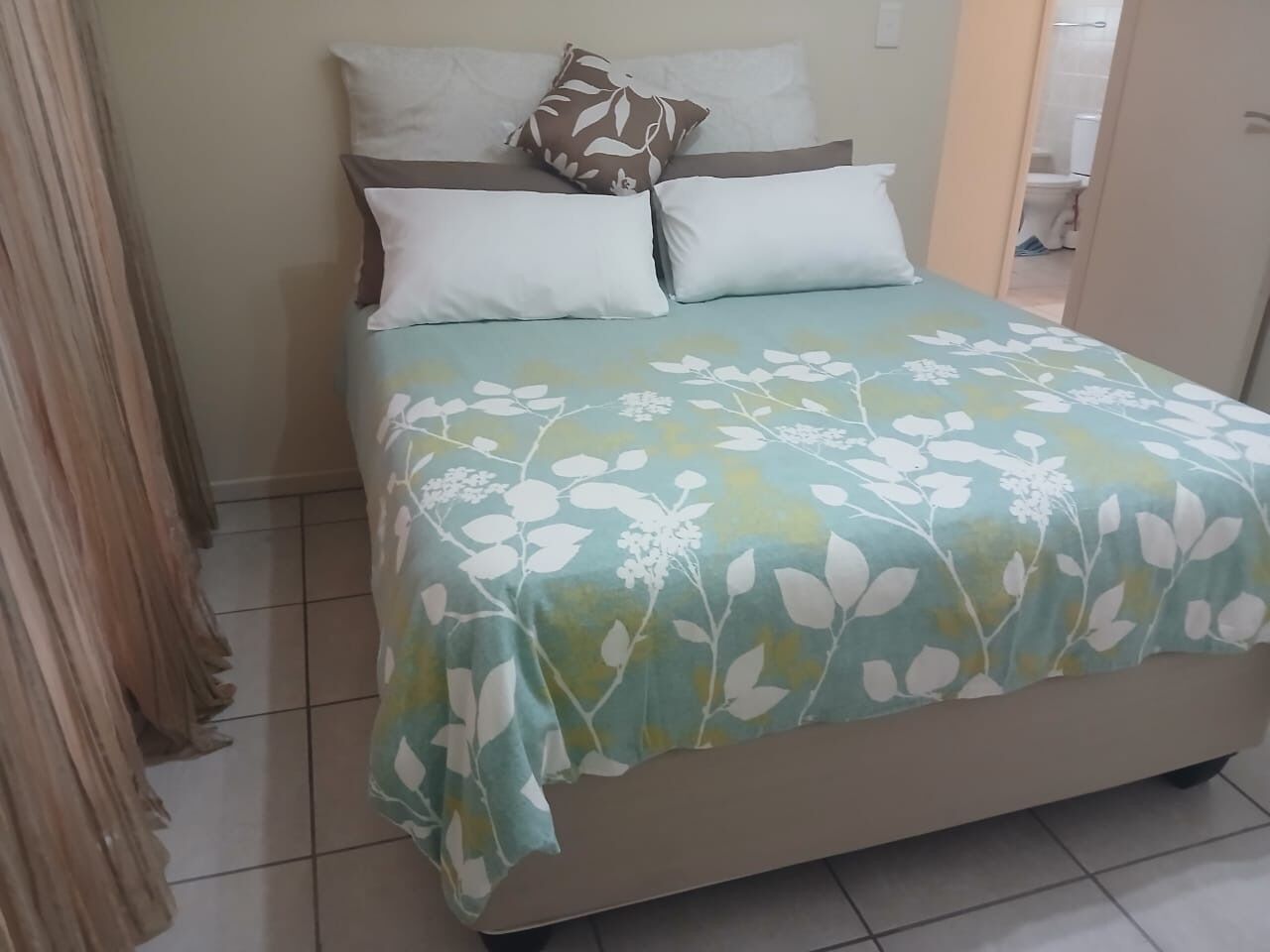 A bed with a floral bedspread, a headboard, and two pillows.