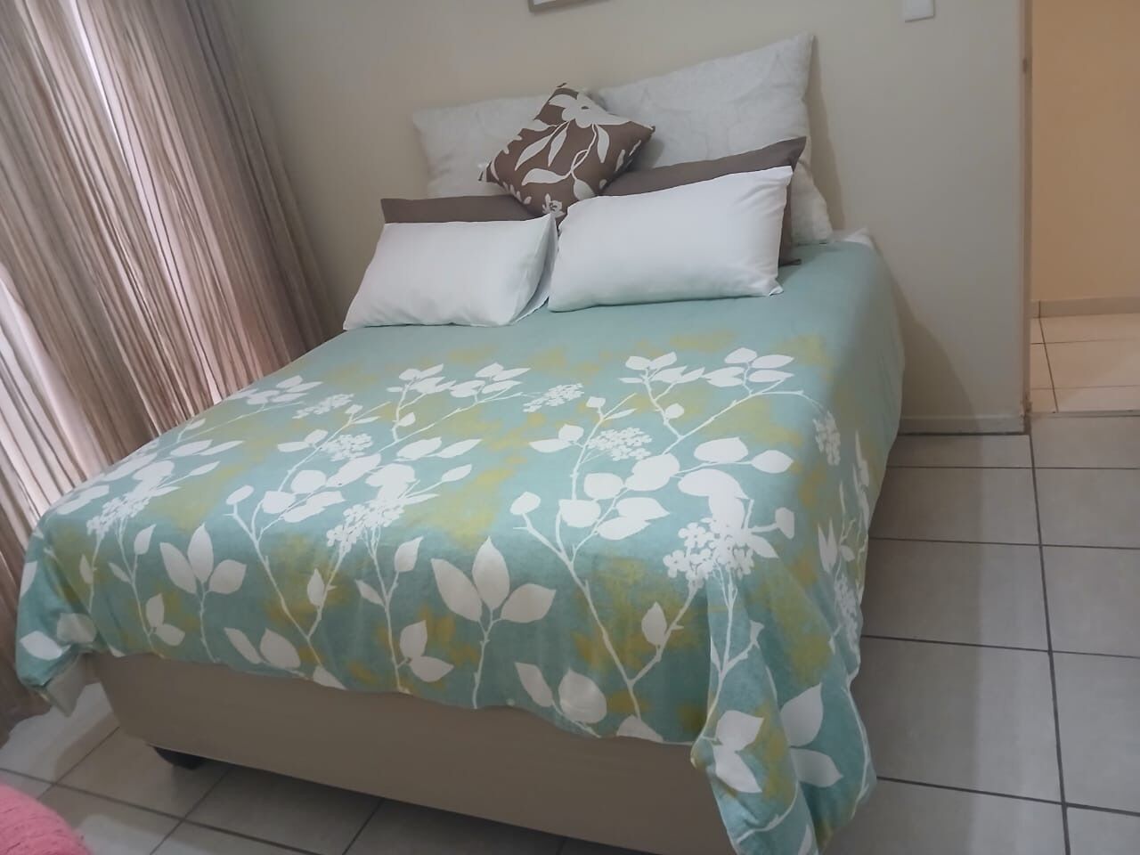 Una cama con una colcha floral, una almohada estampada con flores y una almohada lisa.