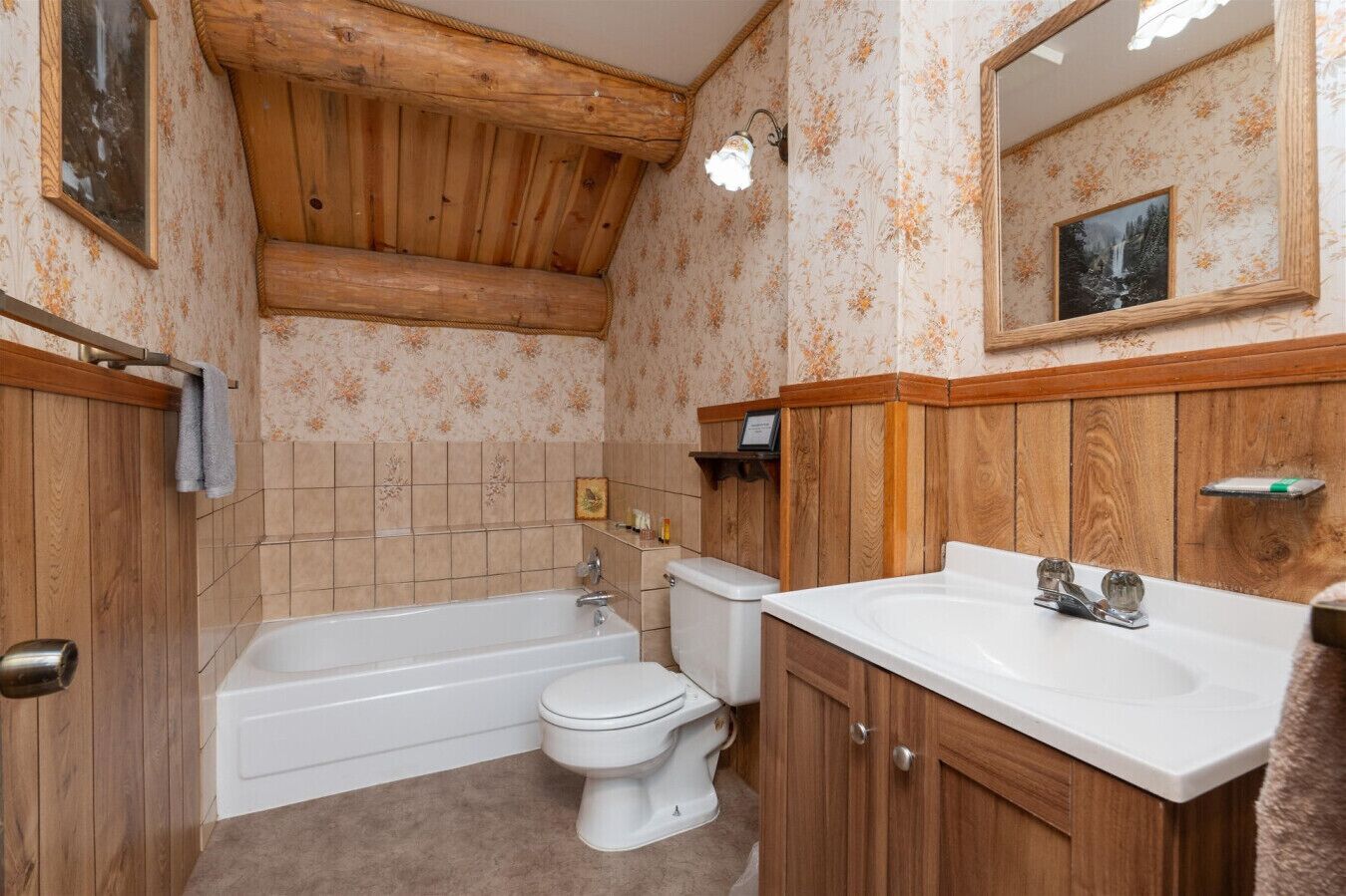Un baño con techo de madera, una bañera, un inodoro y un lavabo con armarios de madera.