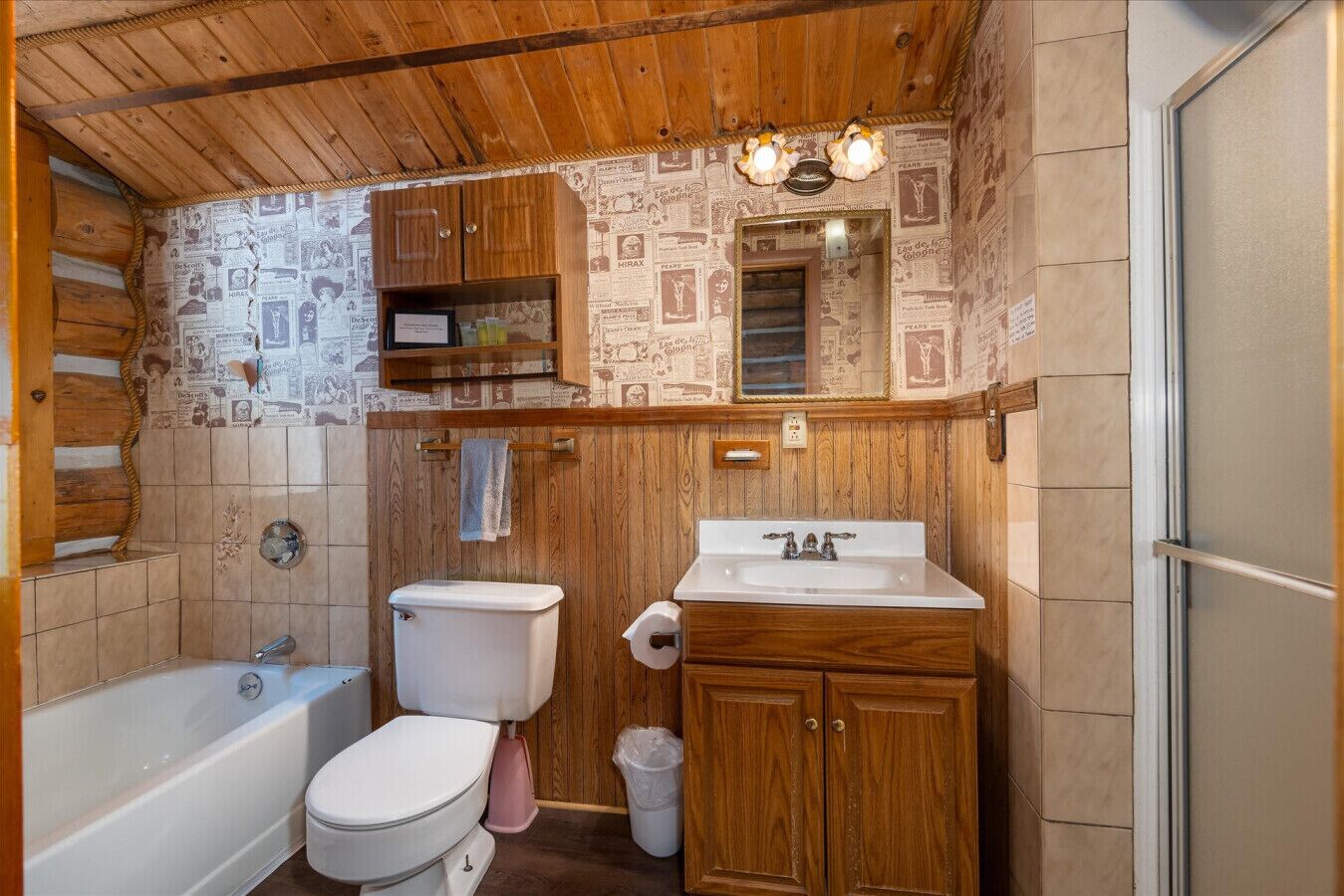 Un bagno con soffitto in legno, un water, un lavandino e una doccia.
