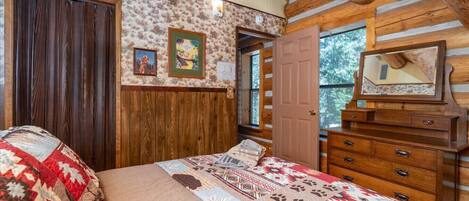 Une chambre à coucher de style chalet, avec un lit, une commode et un miroir.