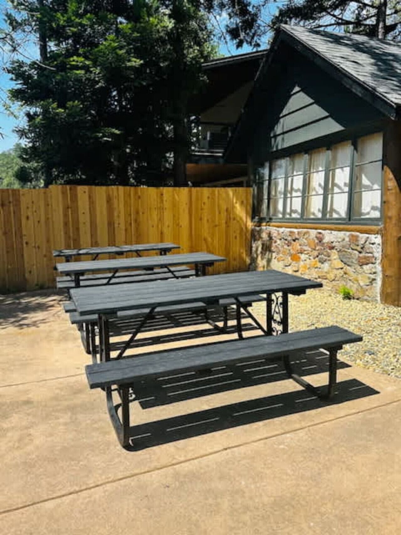 A patio area with picnic tables and a stone wall.
