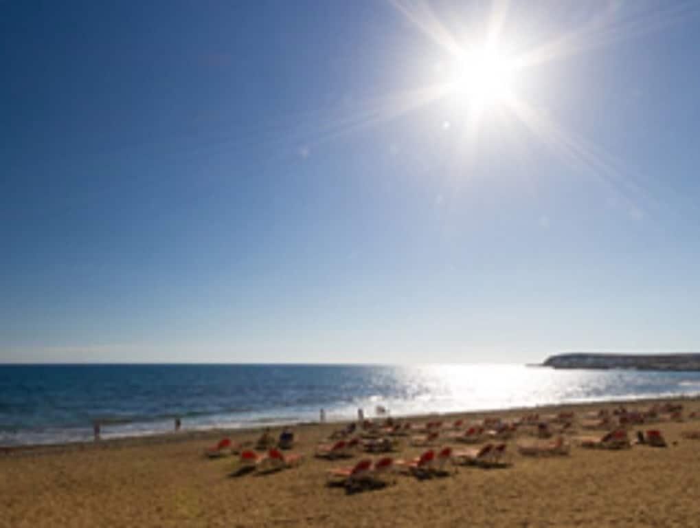 Une plage où des gens se prélassent au soleil, sous un ciel dégagé.
