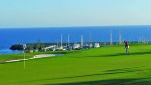 Un terrain de golf avec vue sur l’océan, où une personne joue au golf.