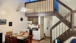 Una cocina compacta con comedor, una escalera y un ventilador de techo.