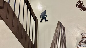 Una escalera con barandilla de madera y un adhesivo mural de una persona caminando.