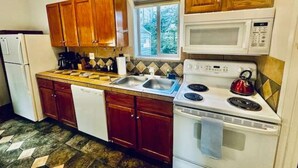 A compact kitchen with wooden cabinets, a microwave, a stove, and a dishwasher. - Yosemite Woods Lower Unit - Inside Yosemite (Yosemite West)