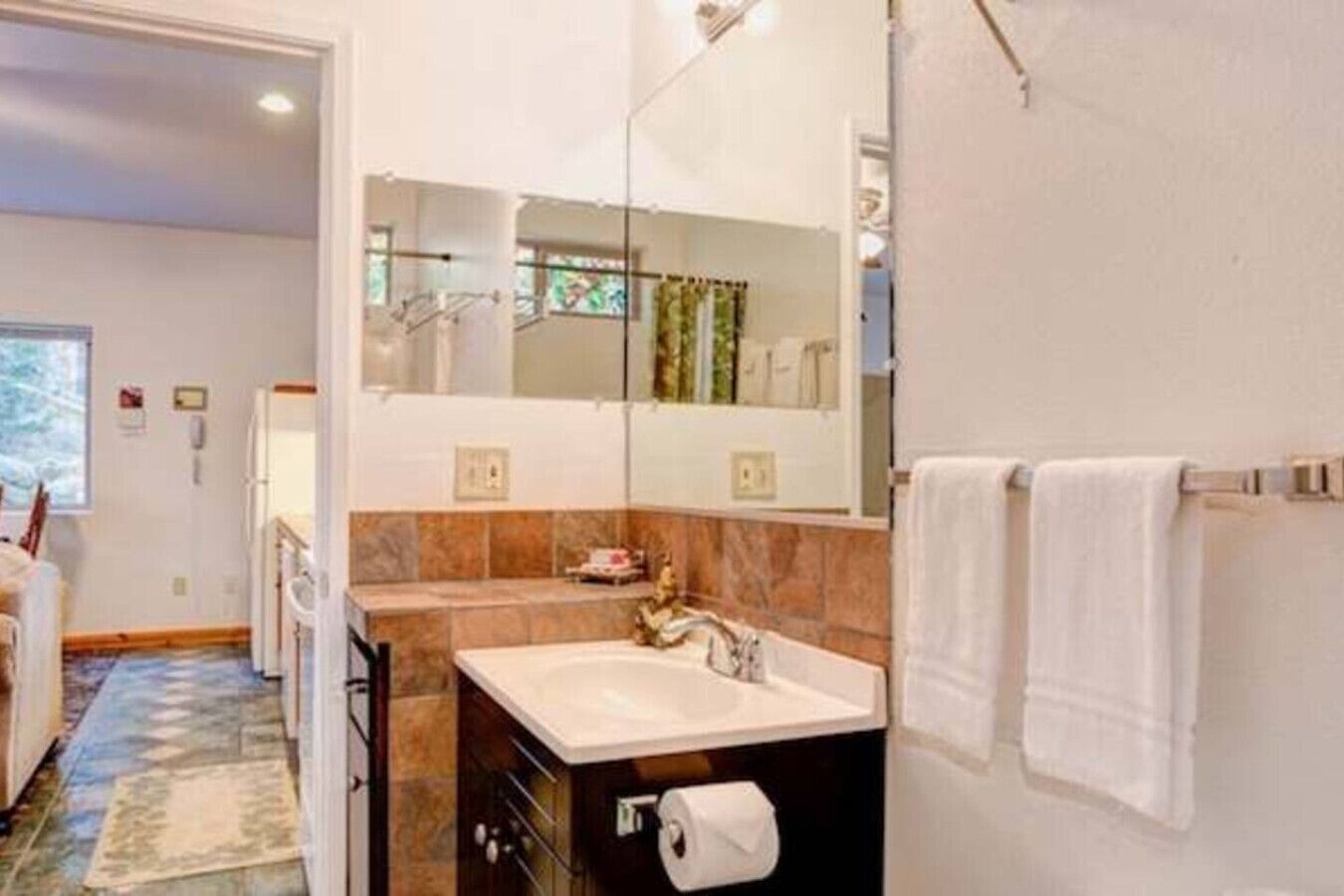 A modern bathroom with a large mirror, a sink, and a toilet.