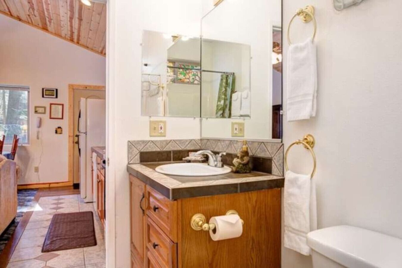 A bathroom with a wooden vanity, a sink, a mirror, and a toilet.
