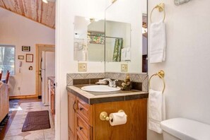 A bathroom with a wooden vanity, a sink, a mirror, and a toilet.