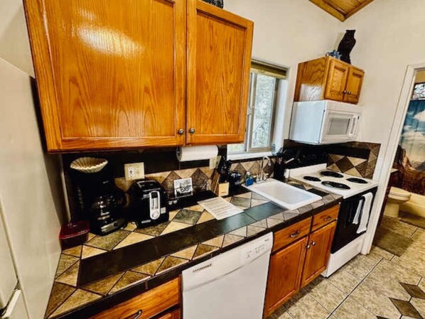 A compact kitchen with wooden cabinets, a microwave, a stove, and a dishwasher.