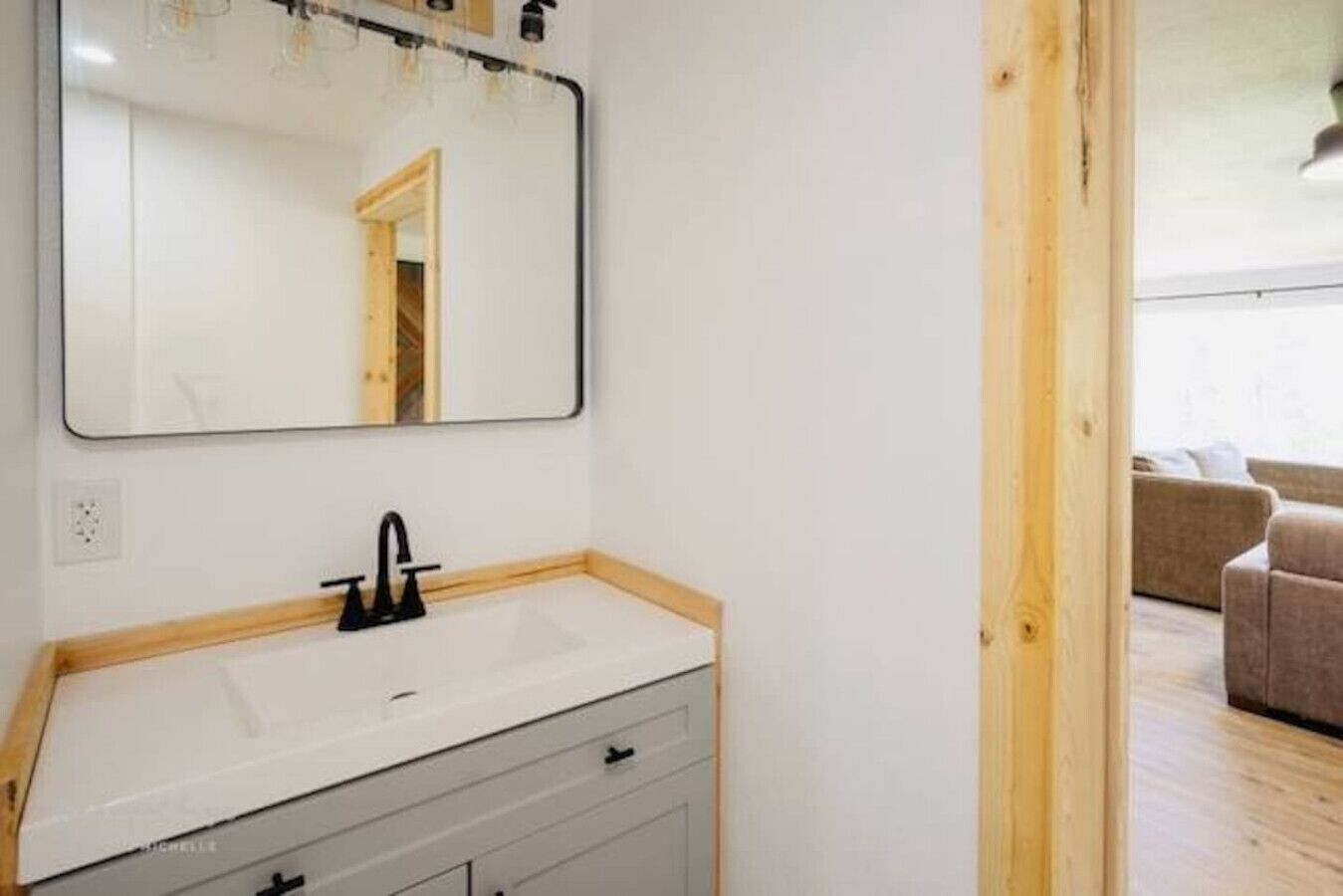 A bathroom with a white sink, black faucet, and a mirror above it.