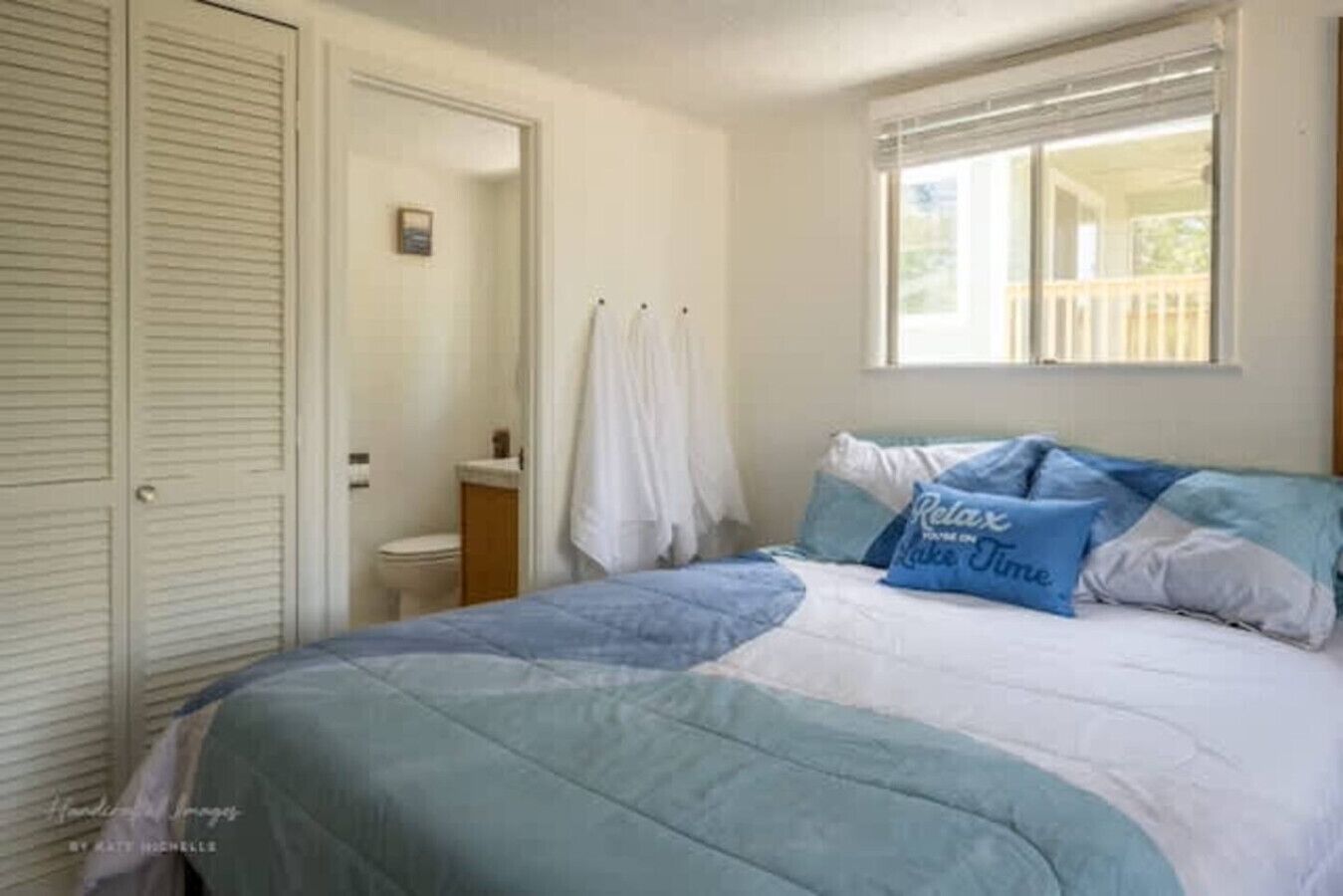 Ein Schlafzimmer mit Bett, einem Fenster mit Blick und einem Badezimmer mit Toilette und Waschbecken.