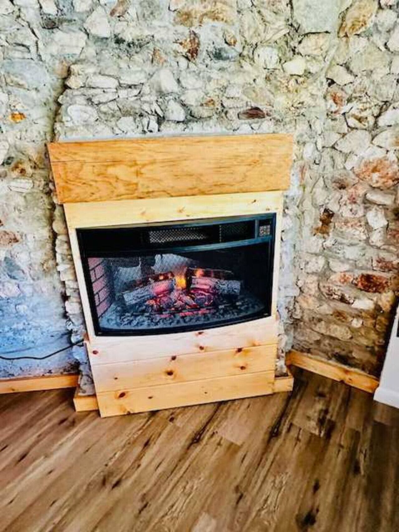 Una estufa de leña con un fondo de pared de piedra.
