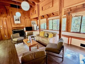 Een knus chaletinterieur met een open haard, houten wanden en grote ramen.